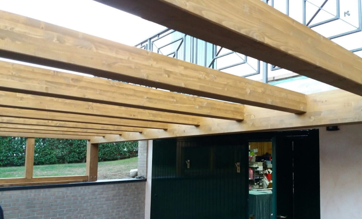 Un tetto in ricostruzione: in altro si vedono le nuove travi in legno, e sotto un garage e il pavimento esterno della'abitazione